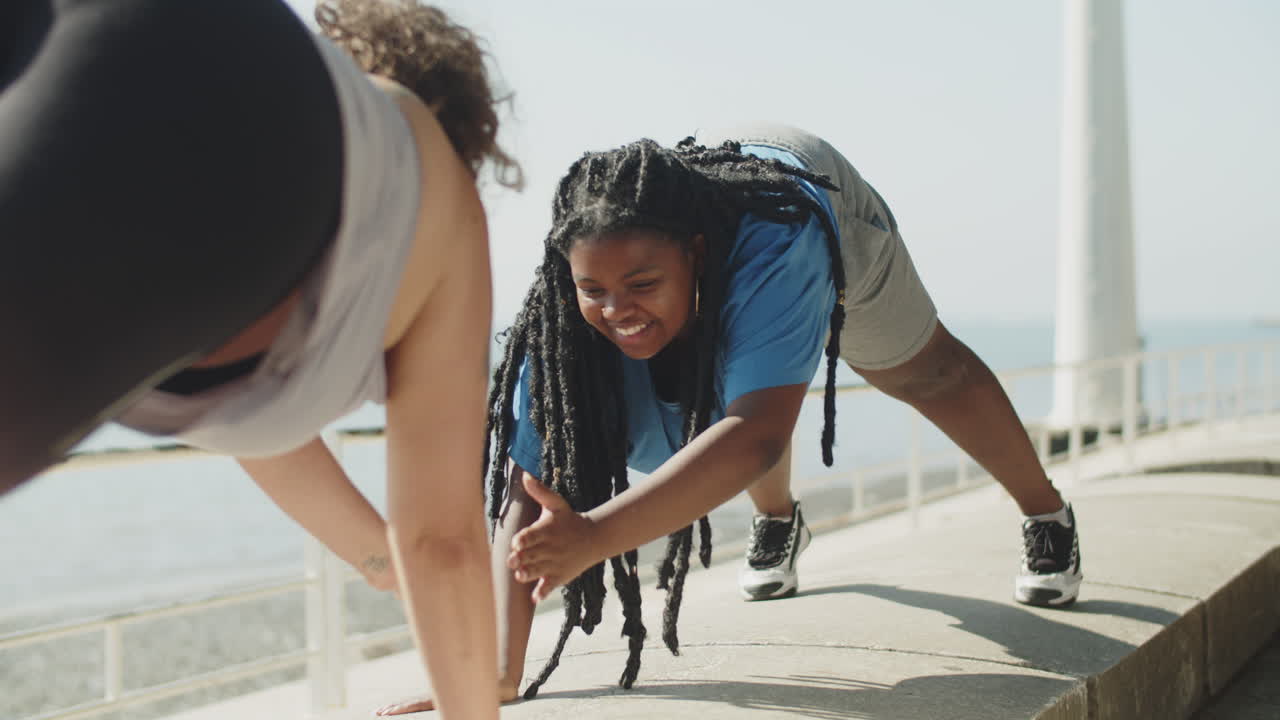 Smiling fat woman standing in plank position with friend in park