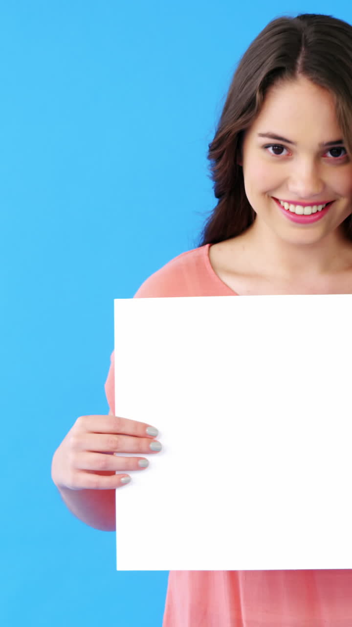 hermosa mujer sosteniendo un cartel en blanco sobre un fondo azul