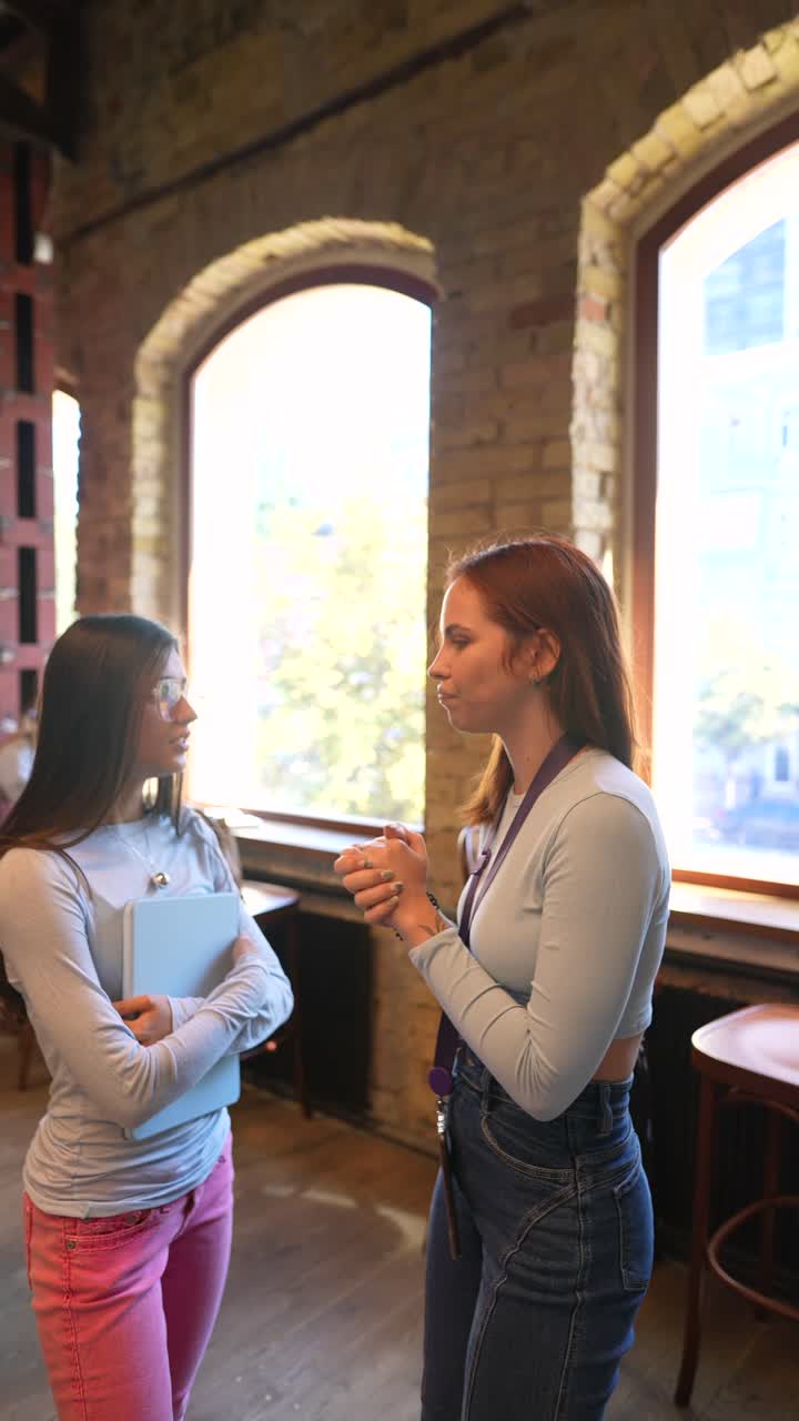 dos chicas adolescentes hablando en una biblioteca