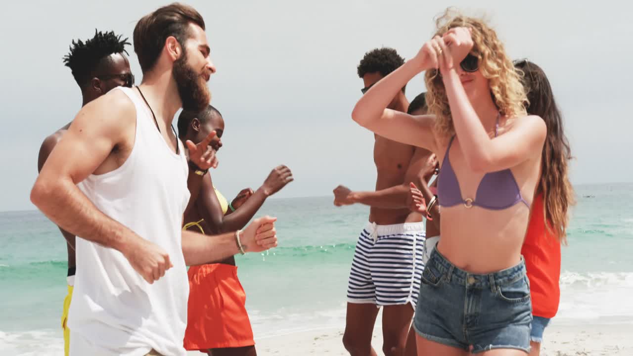 한 무리의 혼혈 친구들이 해변에서 함께 춤을 추고 있습니다.