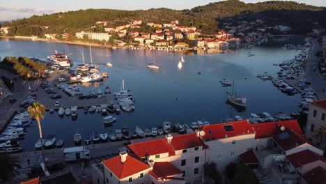 hermosas imágenes de drones filmadas con el sol naciente sobre las brumosas aguas del puerto en una isla croata con niebla sobre el agua y veleros y autos