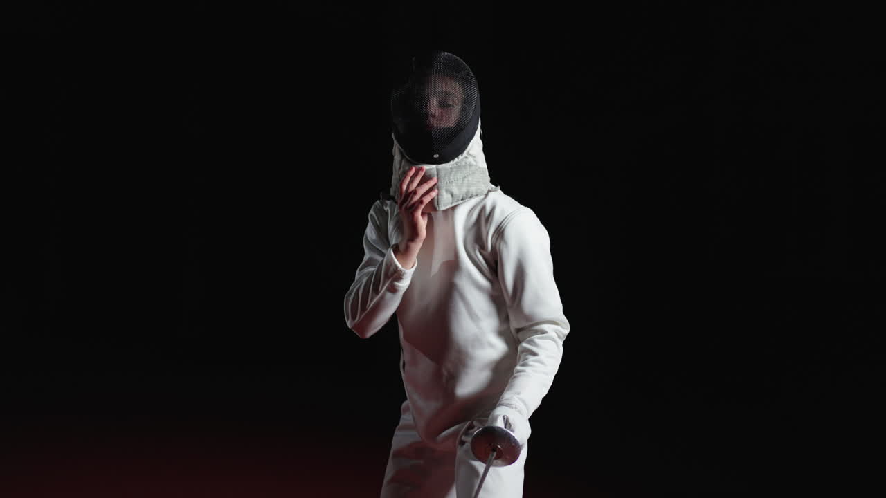 mujer joven en uniforme de esgrima sosteniendo una espada