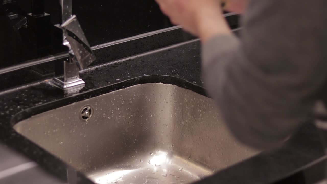 Man Washing Drinking Glass On Modern Sink
