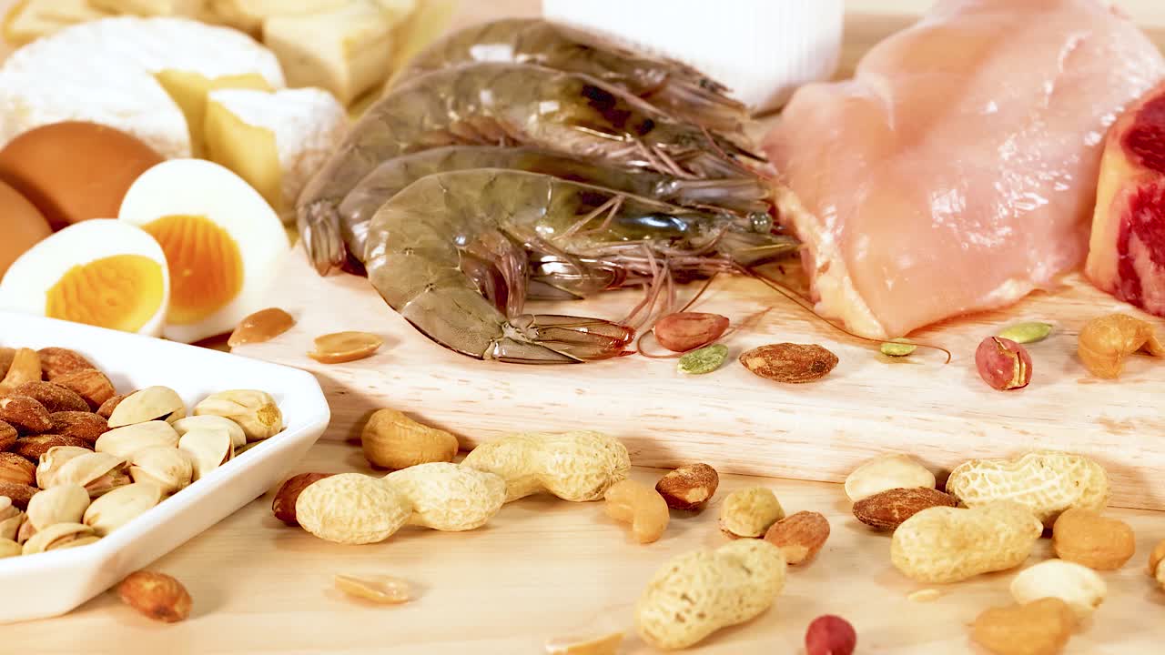 una variedad de alimentos ricos en proteínas, incluidos nueces, mariscos y productos lácteos, están artísticamente dispuestos en una superficie de madera