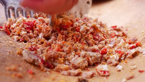 cerca de una persona cortando carne y pimientos rojos para cocinar