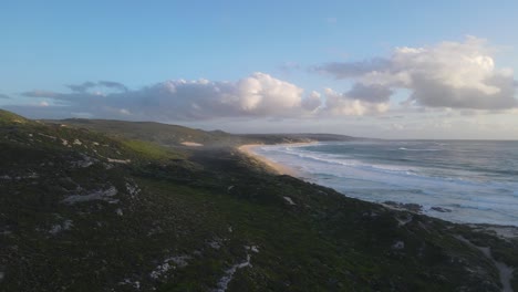 Aerial-flight-along-idyllic-empty-beach-and-crashing-waves-against-shore