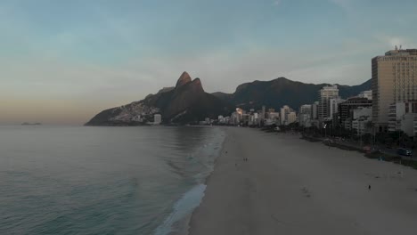 panorama aéreo desde la montaña de los dos hermanos que revela la playa vacía de ipanema a primera hora de la mañana y termina mostrando el lago de la ciudad y la montaña corcovado en río de janeiro al amanecer