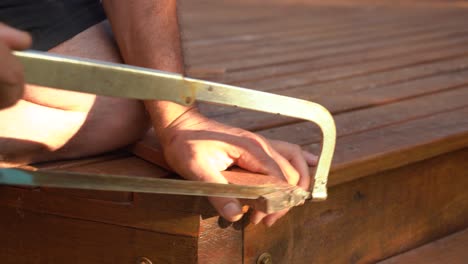 carpenter's hand cutting wood with metal saw