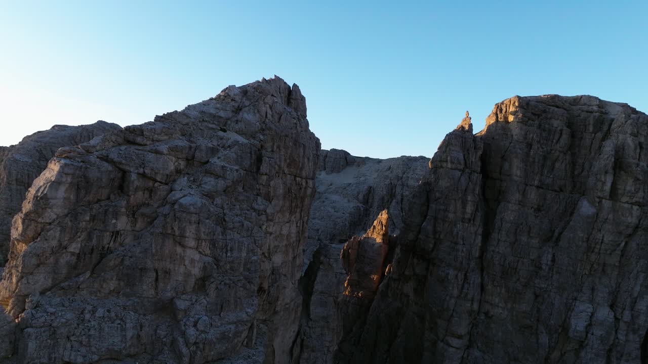 Majestic drone shot of the Dolomites' rugged peaks and ridges, aglow with the soft, warm hues of a fresh sunrise