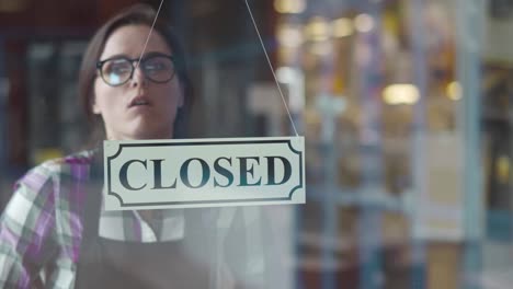 tired female waitress turn open-closed sign on cafe door in evening. realtime