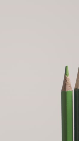 vertical video studio shot of multi-coloured pencils in a line on white background