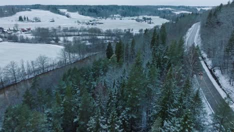 aerial establishing view of valley of the abava river on overcast winter day, fields covered in snow, abava river filled with dark flood water, wide drone shot moving forward, parallax effect