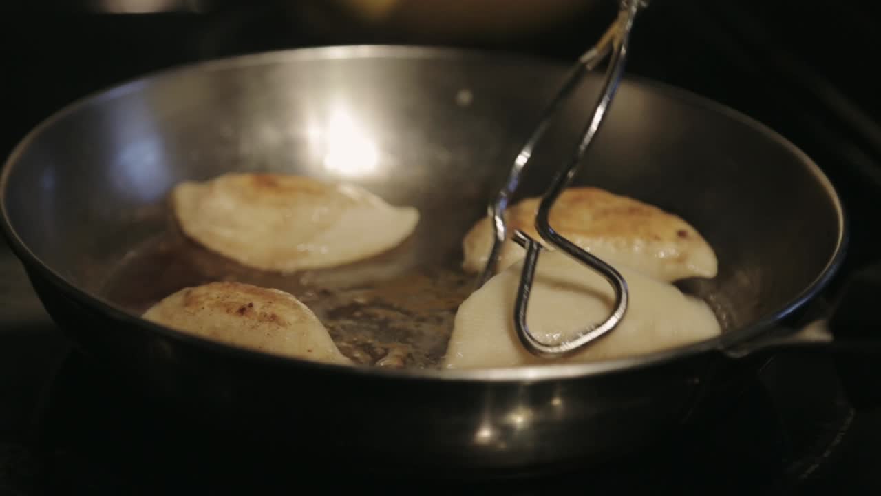 Canada - Chef Flipping The Delicious Dumplings In Stainless Pan Using Clip - Close Up Shot