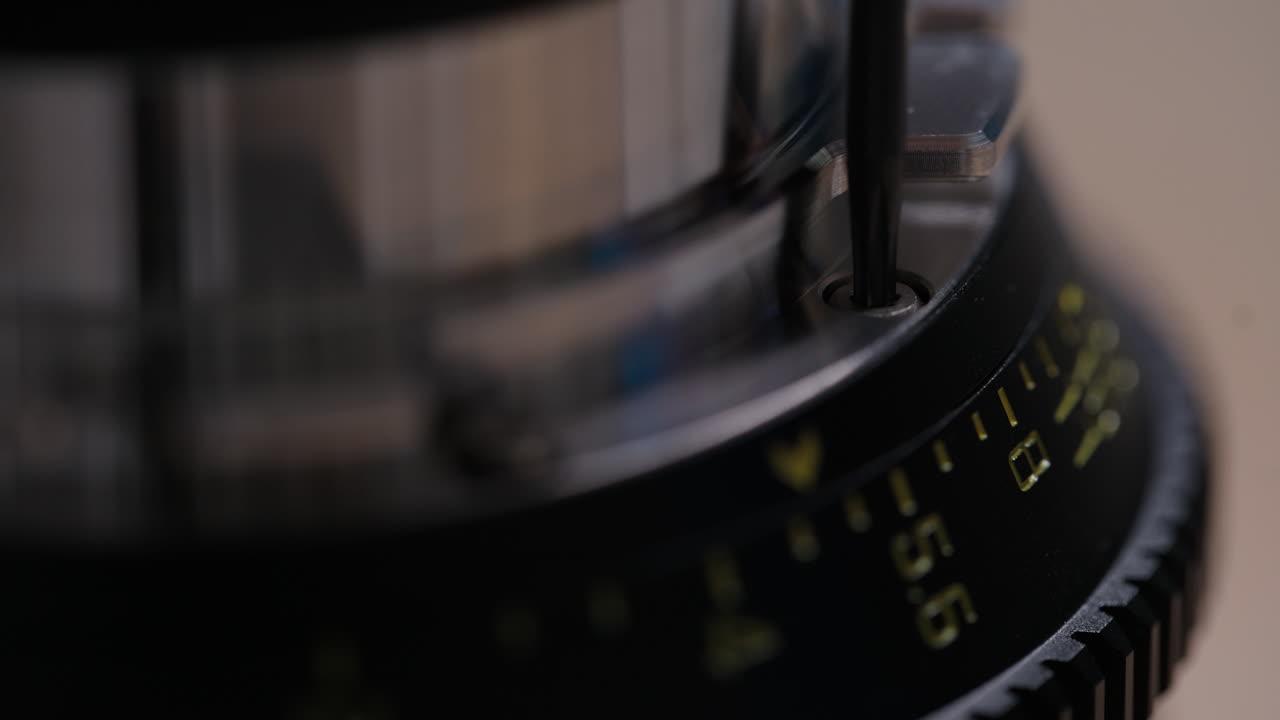 Primo piano estremo di una vite Torx avvitata con cura in un attacco a baionetta PL su un obiettivo cinematografico. Testa della vite e dettagli metallici chiaramente visibili. Filmato di assemblaggio preciso e soddisfacente