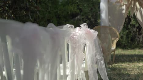 slow revealing shot of decorated chairs ready for an exterior wedding reception