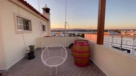 un primer plano de una silla colgante en el acogedor patio de la azotea con zona de salón a primera hora de la mañana