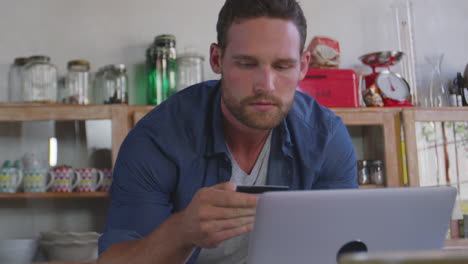 Young-white-man-shopping-on-line-in-kitchen,-close-up,-shot-on-R3D