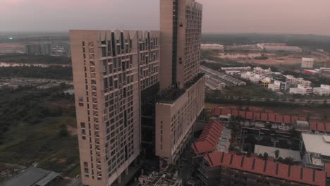 Flying-backwards-at-Tamarind-Suites-Cyberjaya-during-sunrise,-aerial