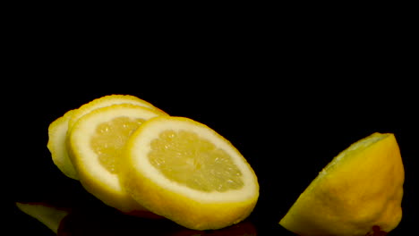 limón en rodajas cayendo a cámara lenta sobre una superficie espejada negra