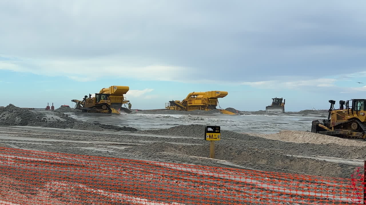 Bulldozer moving sand from pump station, beach replenishment, day