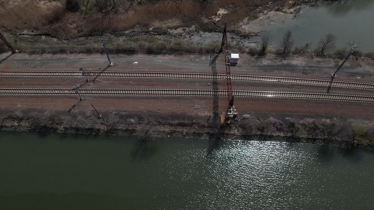 An aerial view of empty train tracks with marsh water on either side of the tracks on a sunny day in the Bronx, New York