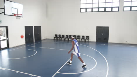 athlete practicing basketball skills on indoor court, focused on dribbling