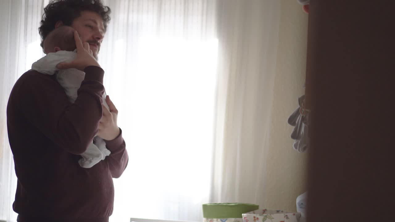Father embracing yawning baby in plaid at home