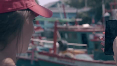 happy-lady-shoots-fishing-boats-and-harbor-on-phone-closeup