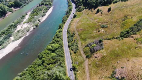 El-Video-Aéreo-Panorámico-Ofrece-Una-Vista-Superior-De-Un-Sereno-Río-Azul-Con-Una-Carretera-Que-Lo-Bordea.