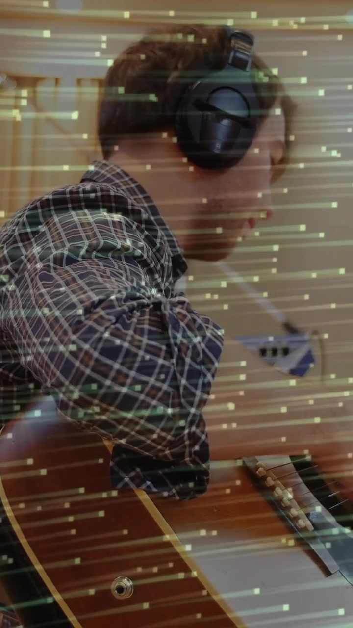 Vertical video: Man placing hands on neck, playing guitar to record while green streaks cross frame