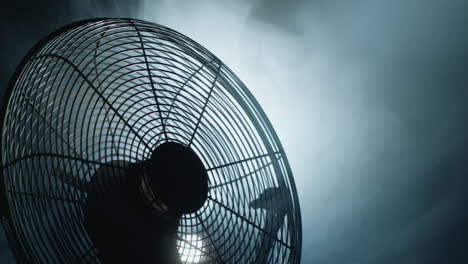 fan blades rotate in rays of light and fog. close-up shot