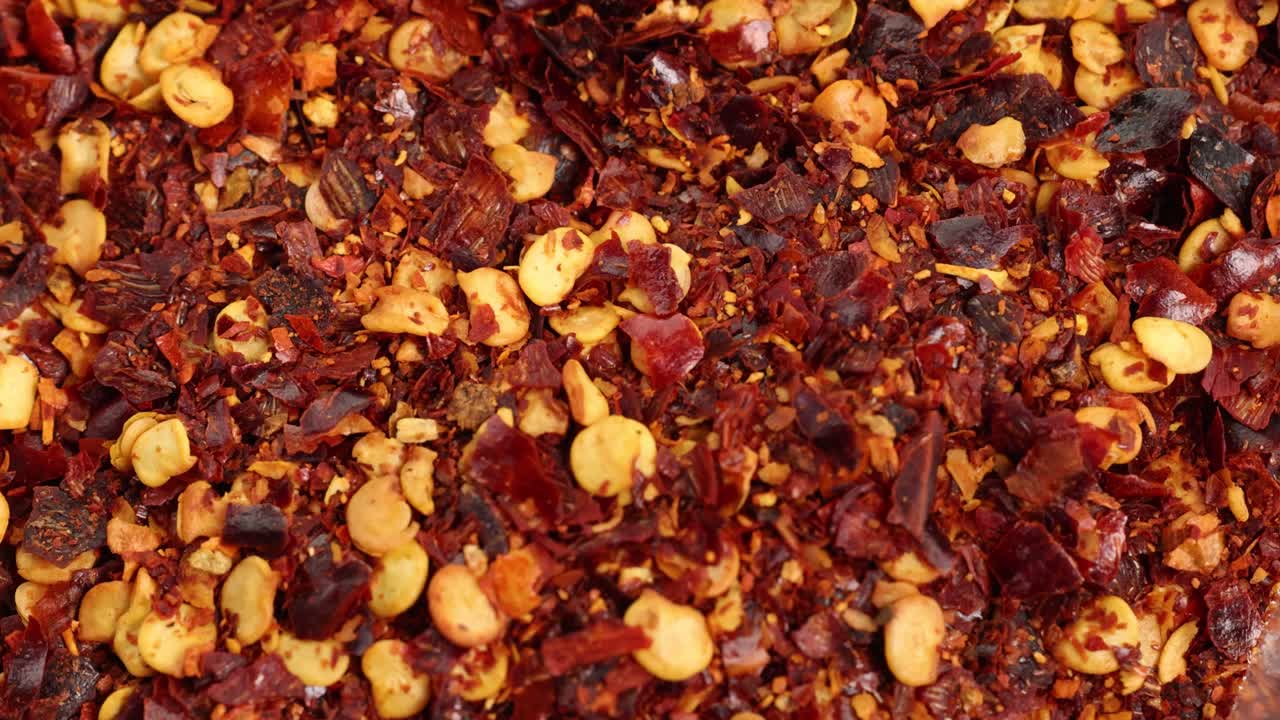 Close-up of chili flakes and seeds cascading, highlighting texture and vibrant colors in detailed macro view