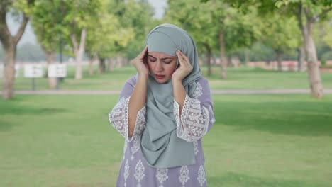 sick muslim woman suffering from headache in park