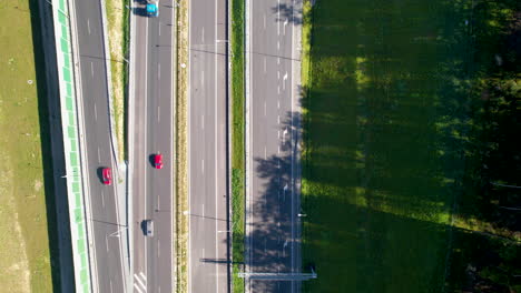 Aerial-flying-over-a-highway-with-multiple-lanes,-surrounded-by-a-grassy-area