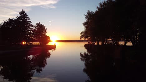 push in drone view at the sun setting above a lake and trees