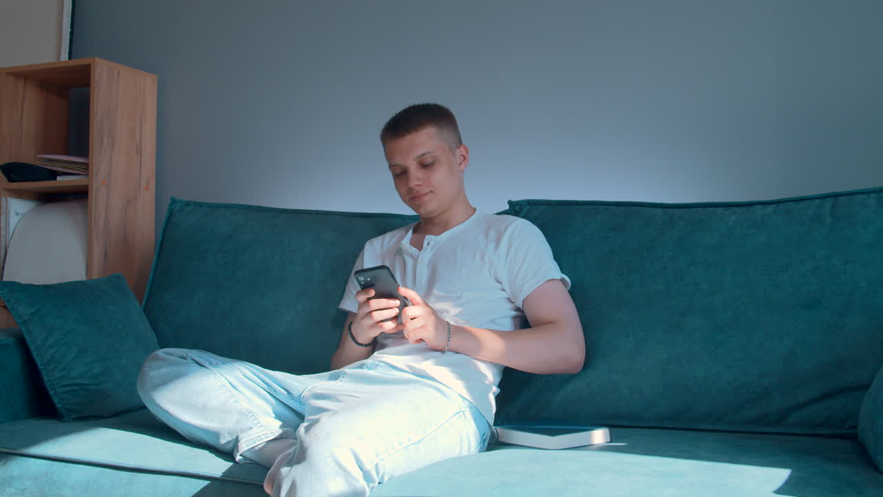 소파에서 스마트폰을 사용하는 십대