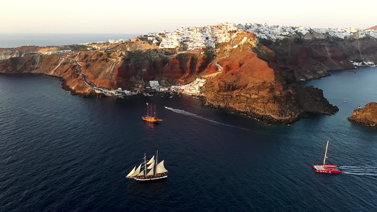 일몰, 산토리니, 사이클레이드, 그리스 동안 깊고 짙은 푸른 에게 해에서 순항하는 아름다운 범선의 항공 드론 뷰 비디오