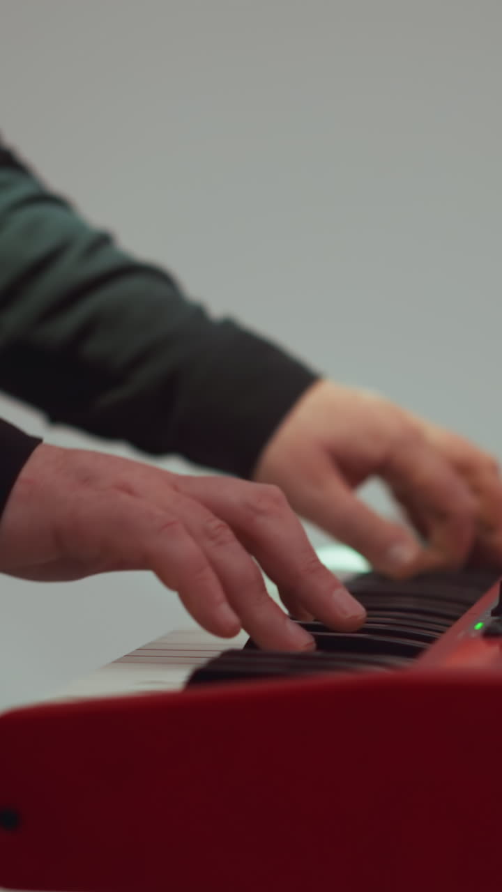 primer plano de manos tocando en un sampler rojo, ambientado contra un fondo suavemente borroso en un estudio sereno