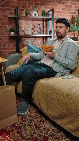 hombre relajándose en el sofá comiendo papas fritas