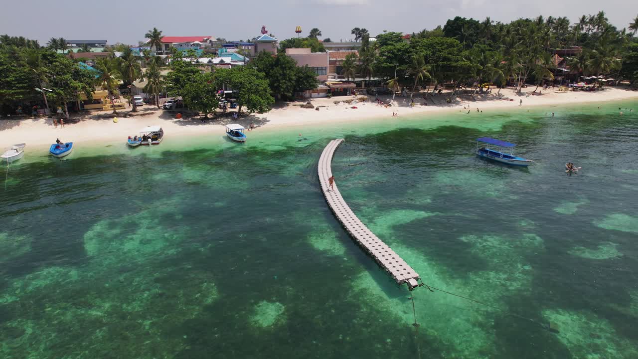 video de drone de 4k de un hombre corriendo a lo largo de un largo muelle de plástico desde la playa de alone en bohol, filipinas