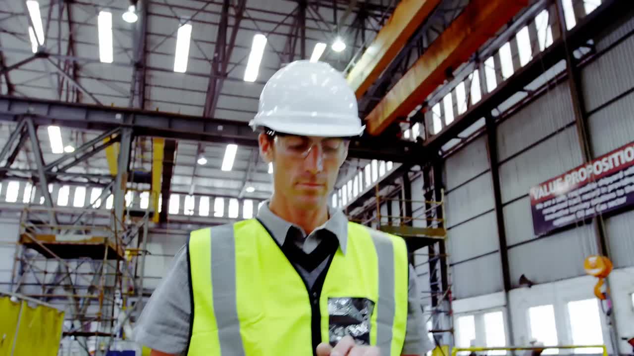 pantalla con procesamiento de datos contra un ingeniero caucásico usando una tableta digital en una fábrica