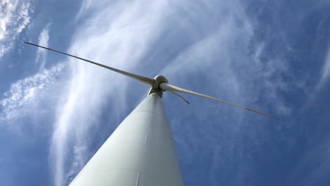 imágenes de primer plano desde abajo de una turbina eólica gigante con tres palas con el cielo y las nubes en el fondo produciendo energía limpia mientras sopla el viento