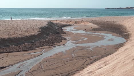 Wasserschleppen-Am-Strand-Machen-Einen-Winzigen-Fluss