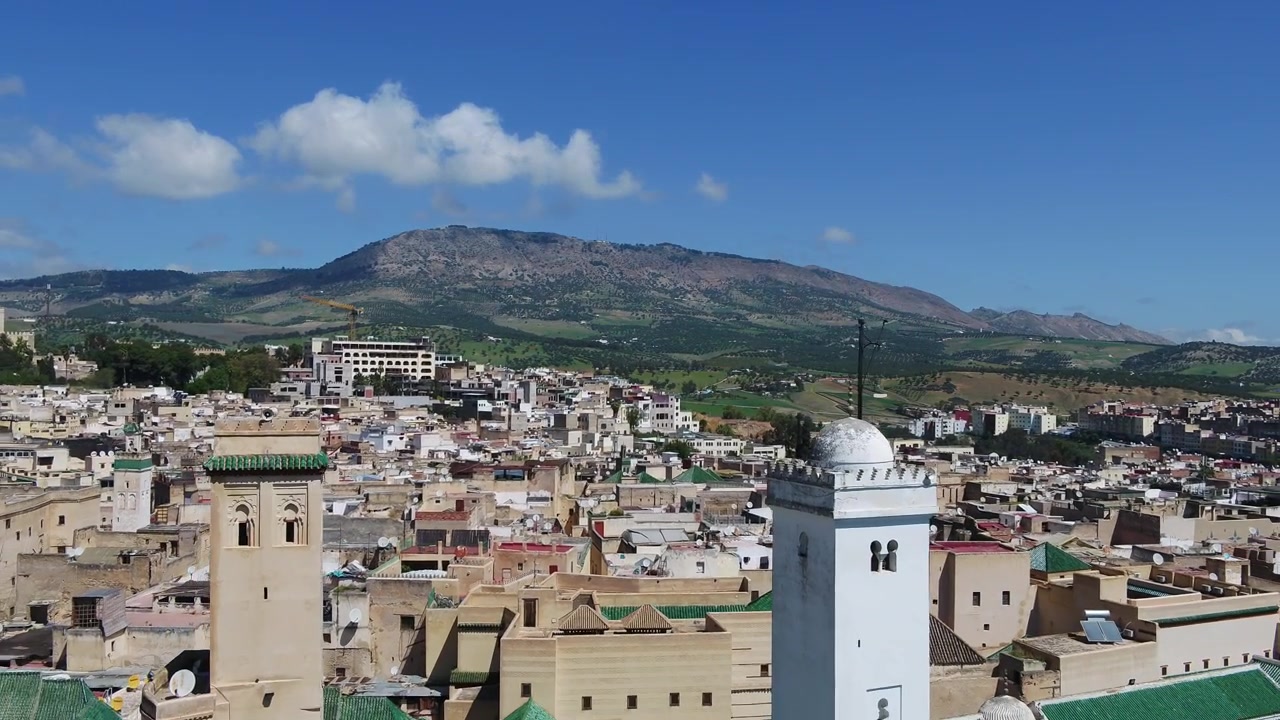 Fas'ta tarihi Fez Medine'sinin üzerinde geleneksel minarelerin dağ manzarası ve mavi gökyüzü ile havadan drone görüntüsü, seyahat projeleri için ideal.