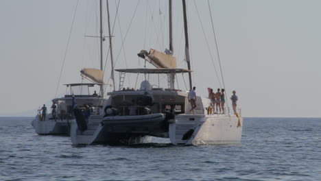 dos kitesurfistas vuelan sus cometas detrás de dos catamaranes de excursión