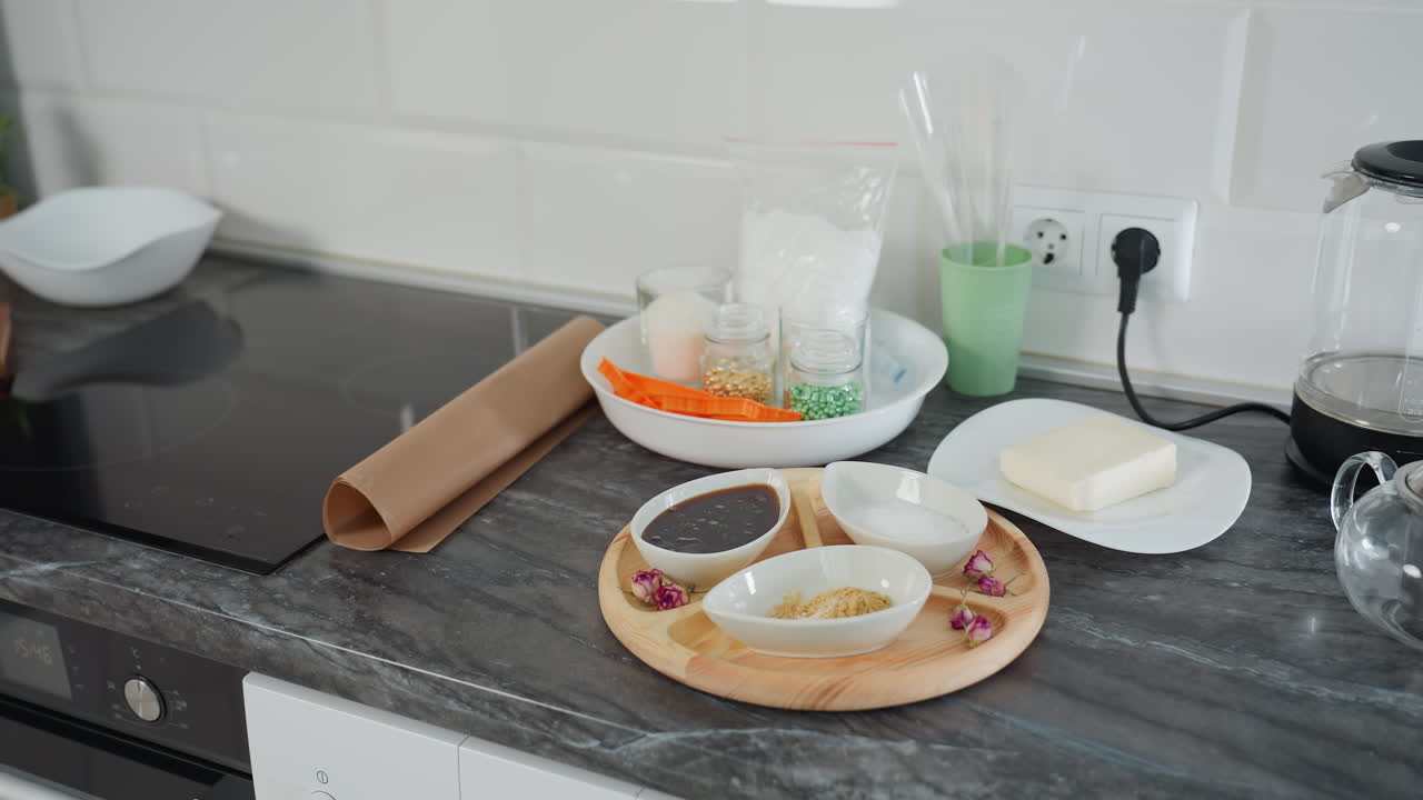 현대적 인 주방 카운터은 향신료, 설탕 및 소스로 가득 찬 세라 그과 함께 나무 트레이, 접시에 버터, 재료, 유리 비 및 요리 도구와 함께 유리 항아리