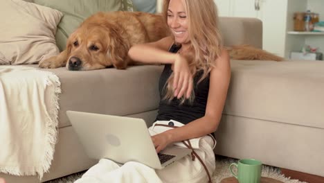 blonde woman is using laptop, computer and working with dog at home