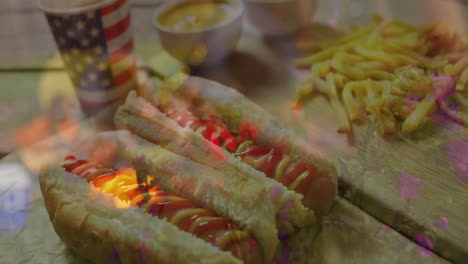 on table, hot dogs with ketchup and mustard, fries, american flag cup
