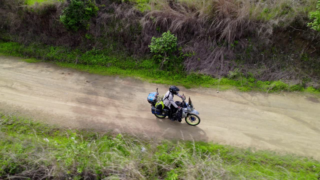 Aerial view of an adventure motorcyclist riding on a remote dirt trail, off road South America