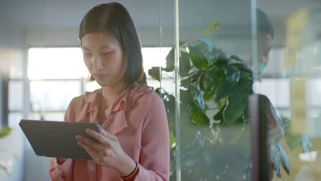 Portrait-of-happy-smart-casual-asian-businesswoman-using-tablet-at-office,-smiling-in-slow-motion